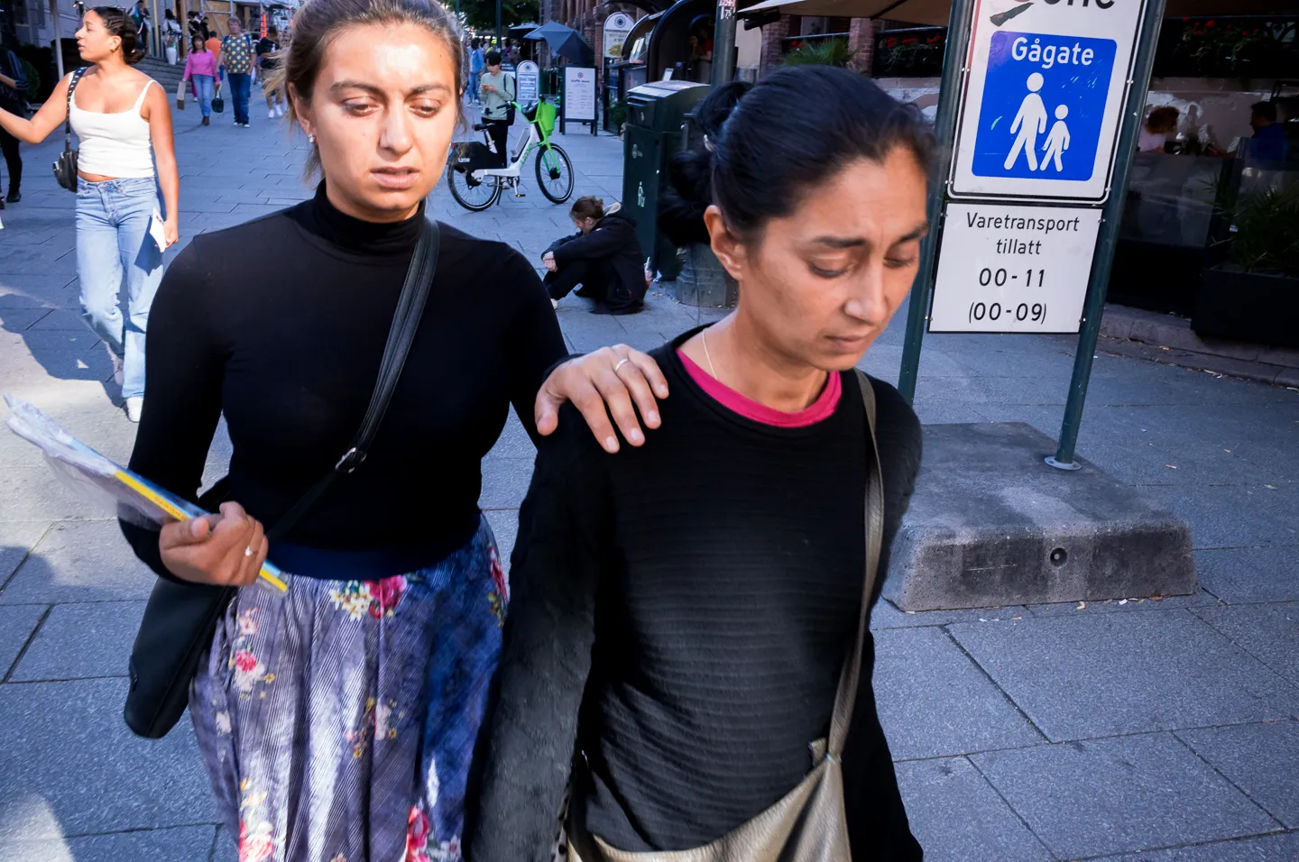 A hand resting on a shoulder in a busy street scene